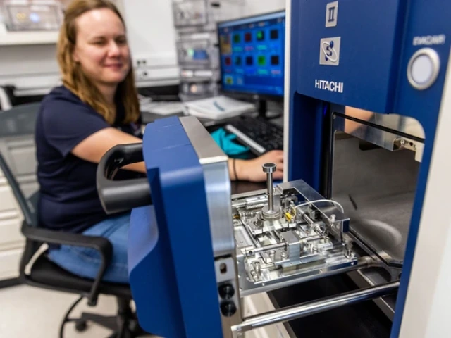 Jessica Barnes sitting in a chair in her lab, loading a sample into an analyzer instrument