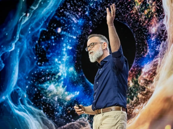 Dante Lauretta gives a presentation in front of a space backdrop