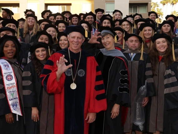 University of Arizona President Robert C. Robbins and College of Veterinary Medicine Dean Julie Funk pose with the college's first graduating class after the Aug. 24 Commencement