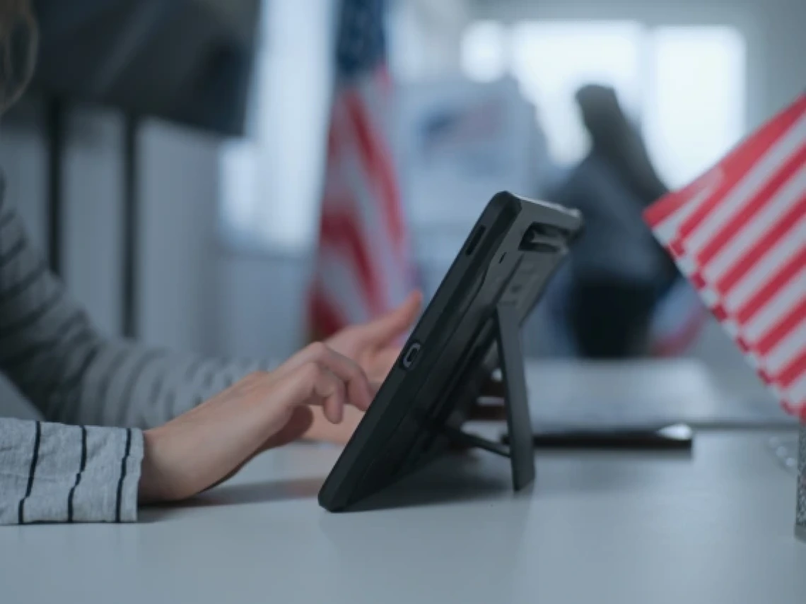 a person using a tablet at a polling location decorated with American flags