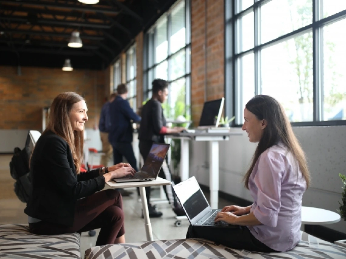 two women on laptops smiling