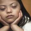 a girl with her eyes closed with her chin resting in her hands