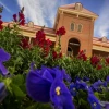 old main rising over a bed of red and blue flowers